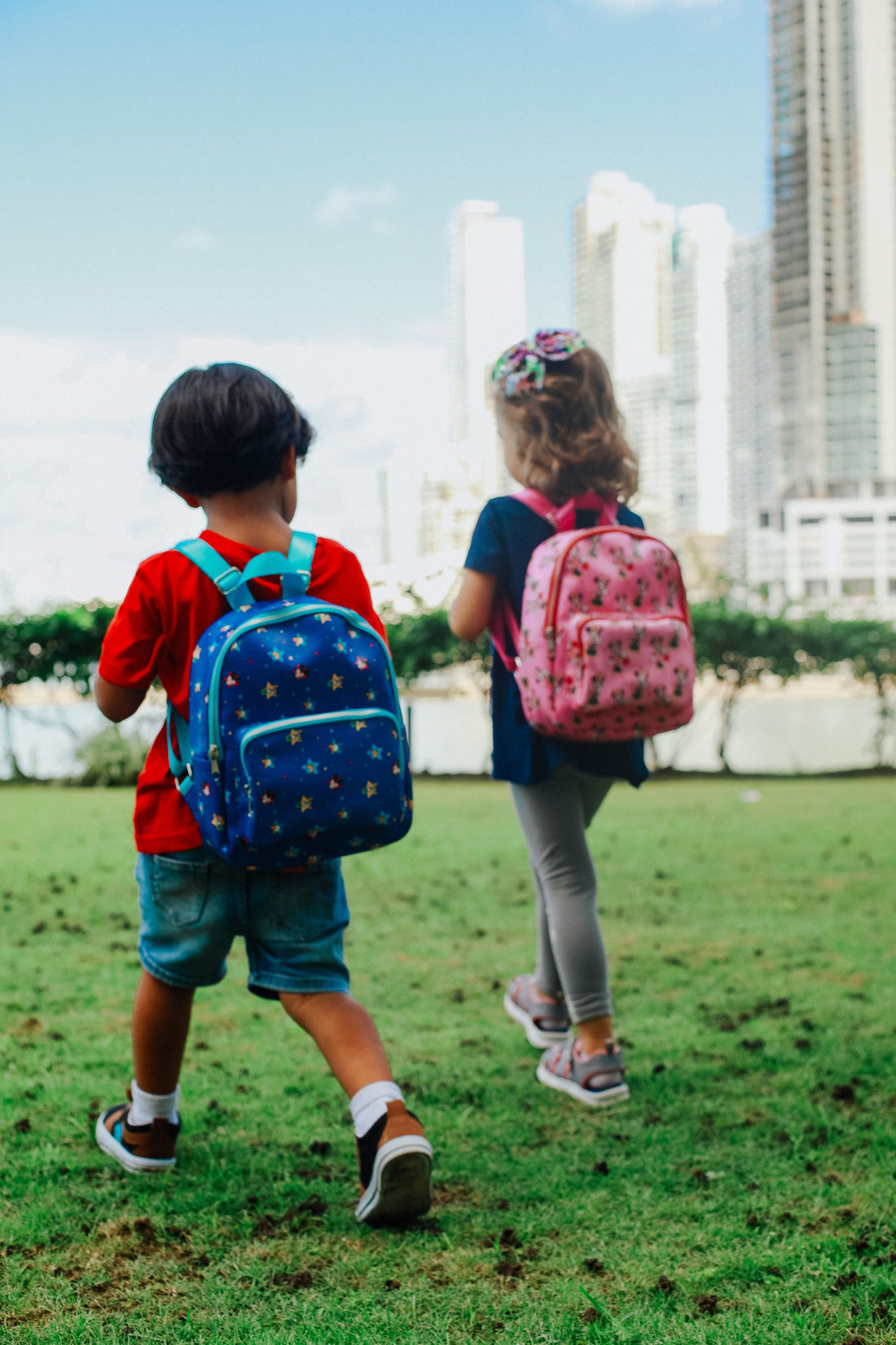 Zwei Kinder mit bunten Rucksäcken laufen gemeinsam durch einen Park – Schulstart Vorbereitung