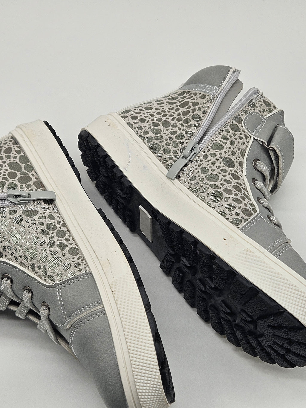Schwarze Lamino Sneaker High mit weißen Sohlen und Schnürung, sportliches Design, auf einer weißen Oberfläche fotografiert